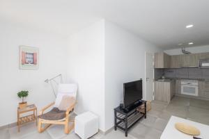 sala de estar con sofá, silla y TV en Lightbooking Apartamento con terraza en playa de Arinaga, en Agüimes