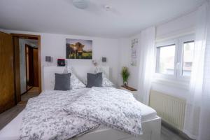 a bedroom with a white bed with a white comforter at Ferienwohnungen KATI in Scheidegg