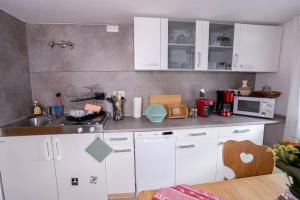a kitchen with white cabinets and a microwave at Ferienwohnungen KATI in Scheidegg