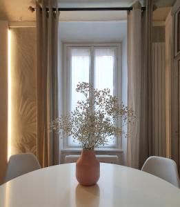un jarrón con flores sentado en una mesa blanca en HomeMi Sant'Ambrogio Apartment en Milán