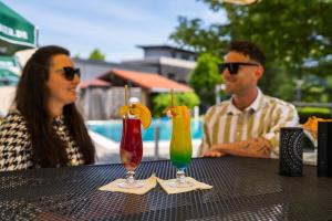 Ein Mann und eine Frau sitzen mit Getränken am Tisch in der Unterkunft Hotel Herzog Heinrich in Arrach