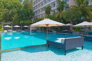ein Pool mit Sonnenschirm und Stühlen sowie ein Hotel in der Unterkunft Paradise Island 1 BR Beach View NE33 in Teluk Nara
