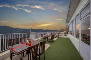 un patio con mesas y sillas en el balcón en Seven Hills Shimla by Him Haults Hospitality en Shimla