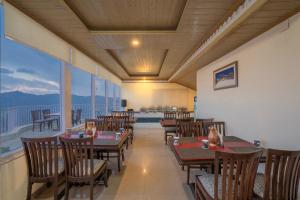 a restaurant with tables and chairs and a balcony at Seven Hills Shimla by Him Haults Hospitality in Shimla