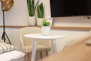 una pequeña mesa blanca con dos plantas en una pared en 2 Apartament Miętowy Rumianek, en Lwówek