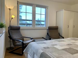 Schlafzimmer mit 2 Stühlen, einem Bett und Fenstern in der Unterkunft Ferienhaus Hete in Staphel