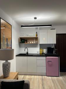 華沙的住宿－Apartament Centrum Warszawy Pereca，厨房配有白色橱柜和粉色冰箱