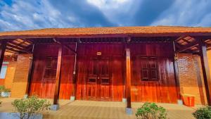 a building with wooden doors on a wooden deck at homstay Hương Rừng in Tân Phú