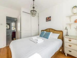 ein Schlafzimmer mit einem weißen Bett und Handtüchern darauf in der Unterkunft Pass the Keys Charming Victorian Gem Near Portobello Market - Explore Notting Hill in Style! in London