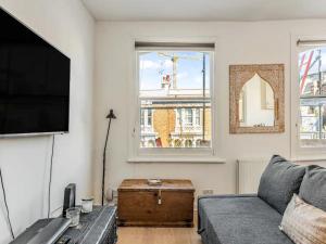 uma sala de estar com um sofá e uma televisão de ecrã plano em Pass the Keys Charming Victorian Gem Near Portobello Market - Explore Notting Hill in Style! em Londres