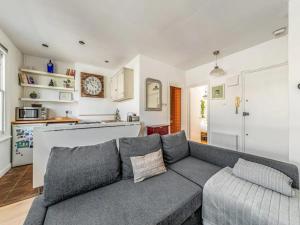 ein Wohnzimmer mit einem grauen Sofa und einer Küche in der Unterkunft Pass the Keys Charming Victorian Gem Near Portobello Market - Explore Notting Hill in Style! in London