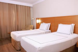 two beds in a hotel room with white sheets at ANEMON KENT EGE in Burunabat