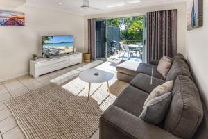 ein Wohnzimmer mit einem Sofa und einem TV in der Unterkunft Sunset Waters Apartments in Hamilton Island
