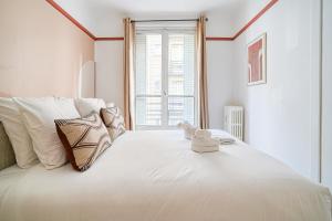 białe łóżko z białymi poduszkami i oknem w obiekcie Apartment next to Palais des Congrès - Neuilly - II w mieście Neuilly-sur-Seine