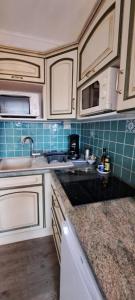 a kitchen with white cabinets and a sink at Studio Meublé Cures thermales avec vue in Gréoux-les-Bains