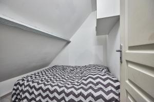 Habitación pequeña con cama blanca y negra. en Blue World - Appt avec terrasse, en Merville-Franceville-Plage