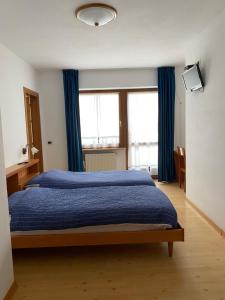 a bedroom with a blue bed with blue curtains at Garní Ladinia in Pescul
