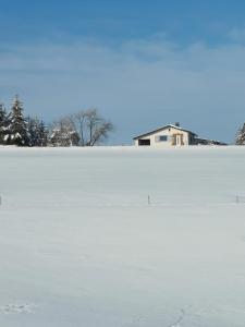 a field covered in snow with a house in the background at Auszeit, Erholung mitten in der Natur - Ferienhaus im Sauerland in Faulebutter in Finnentrop +18 photos