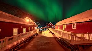 an aurora shines in the sky over a city with buildings at Ure Lodge in Sennesvik