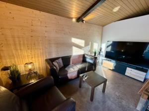 sala de estar con sofá y TV de pantalla plana en Ferienwohnung Brunni-Lodge direkt am Grossen Mythen en Alpthal