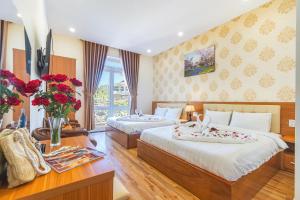 Villa Hoa Ly Đà Lạt في دالات: غرفة نوم بسريرين وطاولة مع ورد