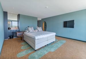 Dormitorio azul con cama y TV en Van der Valk Hotel A4 Schiphol, en Hoofddorp