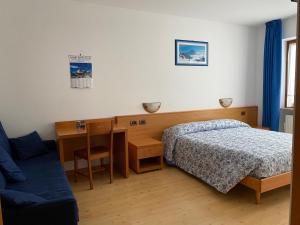 a bedroom with a bed and a desk and a table at Garní Ladinia in Pescul
