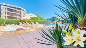 陽光海灘的住宿－Bratanov Summer Apartment，一座带白色桌椅和鲜花的游泳池