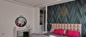 - une chambre avec un lit doté d'oreillers roses et d'un miroir dans l'établissement Villa B&B, à Sousse