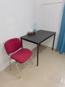 una silla roja sentada frente a un escritorio negro en Big bedroom in apartment sharing washroom, en Sharjah