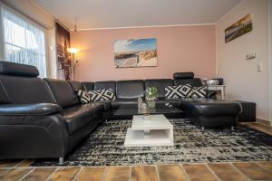 a living room with a black leather couch and a table at Ferienhaus Seeschwalbe, FeWo Vermittlung Nordsee in Dangast