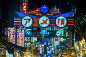 una strada cittadina di notte con insegne al neon di stayme THE HOTEL Ueno a Tokyo