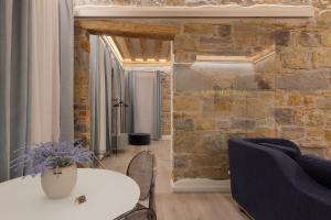 una camera con un muro in pietra e un tavolo con sedie di San Nicolò Suites a Trieste