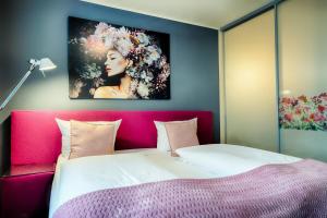 a bedroom with a large bed with a pink headboard at Hotel Fürst Garden in Dortmund