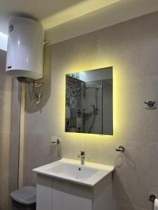 een badkamer met een witte wastafel en een spiegel bij SKetch Apartments in Durrës