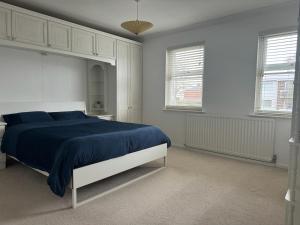een slaapkamer met een bed met blauwe lakens en 2 ramen bij Stratford upon Avon: 2 bed town centre apartment, parking for one car in Stratford-upon-Avon