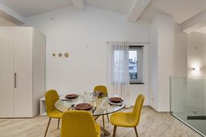 uma sala de jantar com uma mesa de vidro e cadeiras amarelas em The Harbor Houses by Wonderful Italy em Gênova