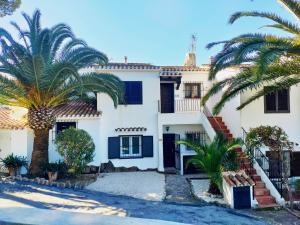 een wit huis met palmbomen ervoor bij Casita Leo in Teulada