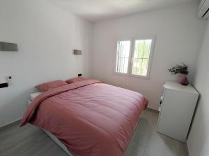 een slaapkamer met een roze bed en een raam bij Casita Leo in Teulada