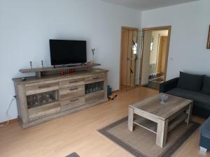 sala de estar con TV, sofá y mesa en Ferienhaus Ulbricht beim Senftenberger See, en Hosena