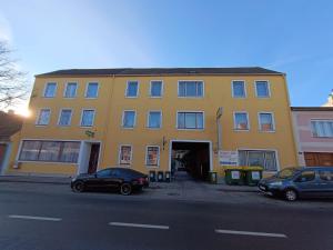 een geel gebouw met auto's ervoor geparkeerd bij Pension Eder in Bruck an der Leitha