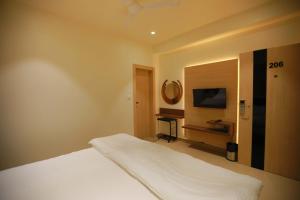 a bedroom with a white bed and a television at Hotel Adora in New Delhi