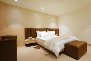 a bedroom with a large bed and a chair at Hotel Adora in New Delhi