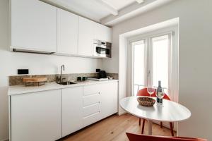 a white kitchen with a table and red chairs at La casa di Piera in Como
