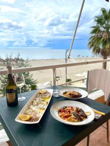 een tafel met borden eten en wijn en een strand bij SKetch Apartments in Durrës