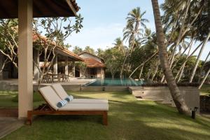 a lounge chair and a pool in a backyard at Kirana - A Santani Villa in Bentota