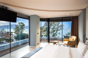 a bedroom with a large bed and large windows at Yacht Hotel in Vlorë
