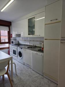 a kitchen with white appliances and a table at Zona centro con plaza de garaje VUT3983AS in Gijón