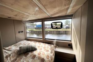 1 cama en el medio de una habitación con ventana en Luxus Hausboot mit Jacuzzi, en Kolonie Zern