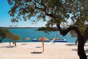 a beach with umbrellas on the sand and the water at Turismo Rural Pedremoura in Vila Ruiva